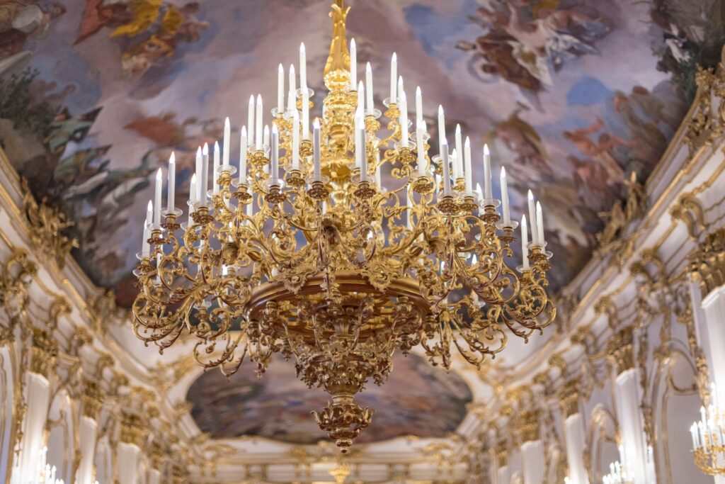 Colorful frescos on the ceiling of Schonbrunn Palace in Vienna, Austria, with a huge gold chandelier.