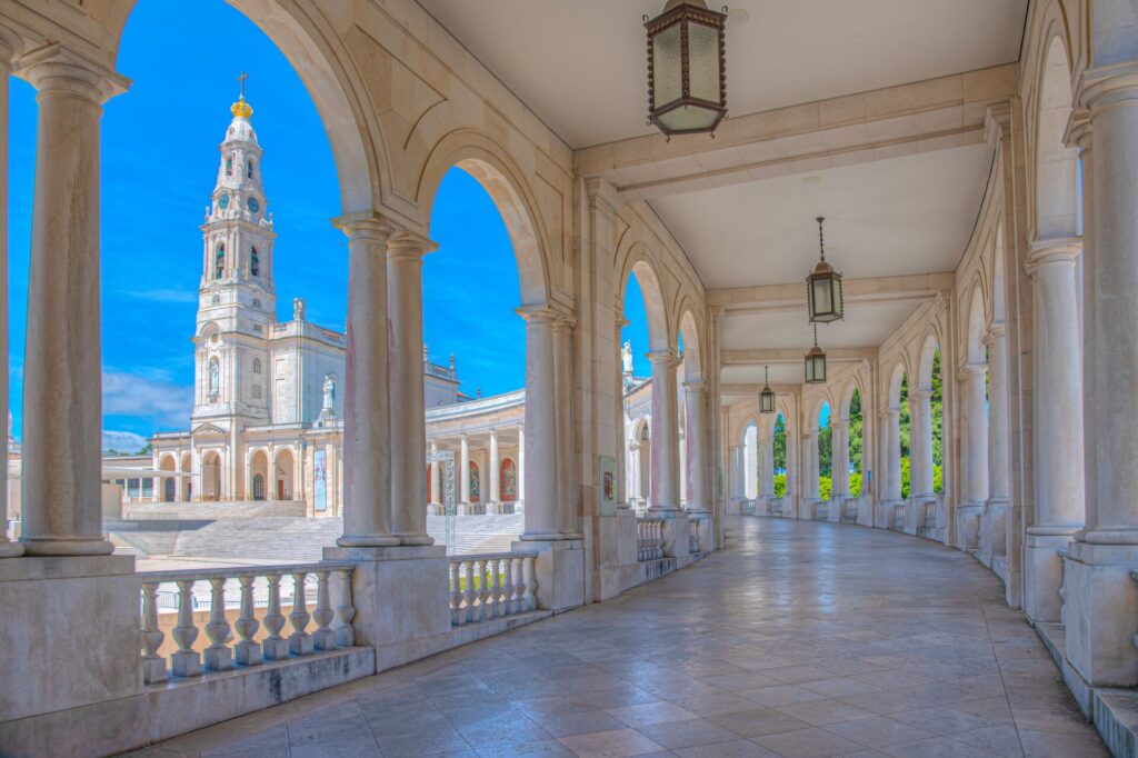 White columns of a palace in Portugal, with marble floors and a large white tower in the background.