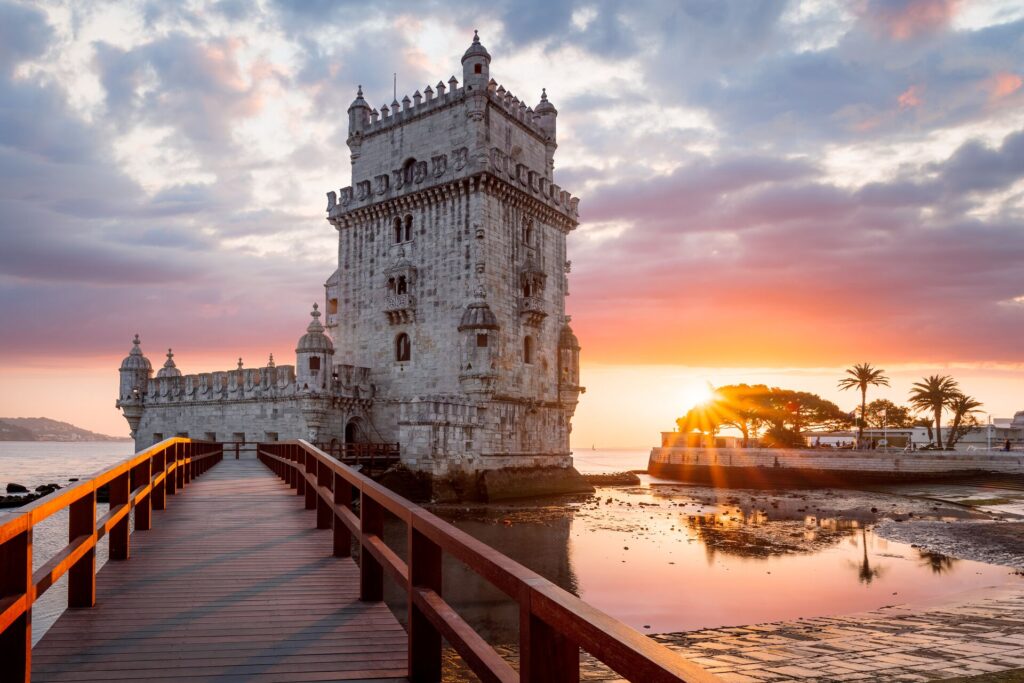 The white Torre de Belem on Lisbon's waters in the pink glow of sunset.