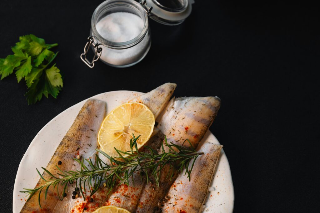 Pieces of fish served on a plate with a lemon wedge.