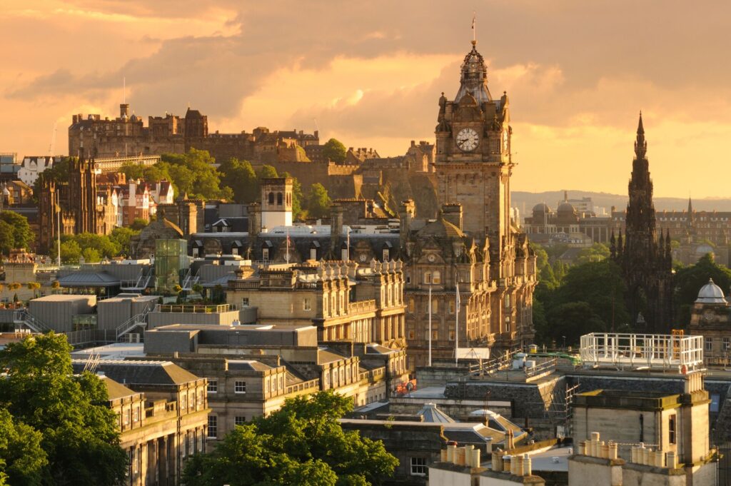 A cityscape showing a large clock tower and Edinburgh Castle in the background.