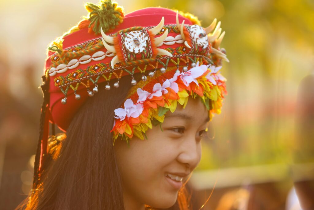 Taiwanese woman wearing traditional hat adorned with petals and shells and bells