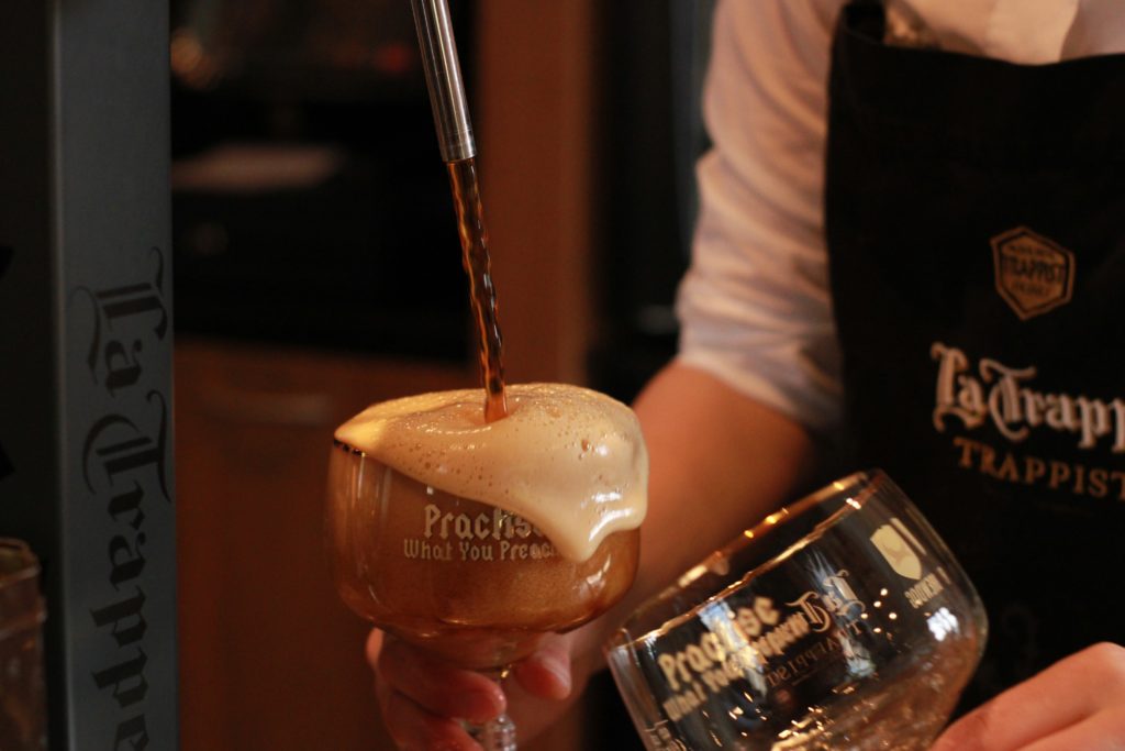 Close up image of beer being poured, showing a person wearing an apron saying Trappist.