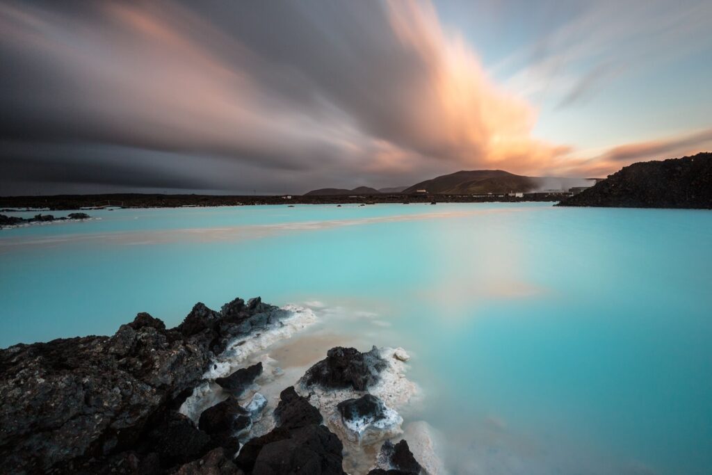 Ethereal blue geothermal waters flanked by black rocks under a cloudy sky in Iceland