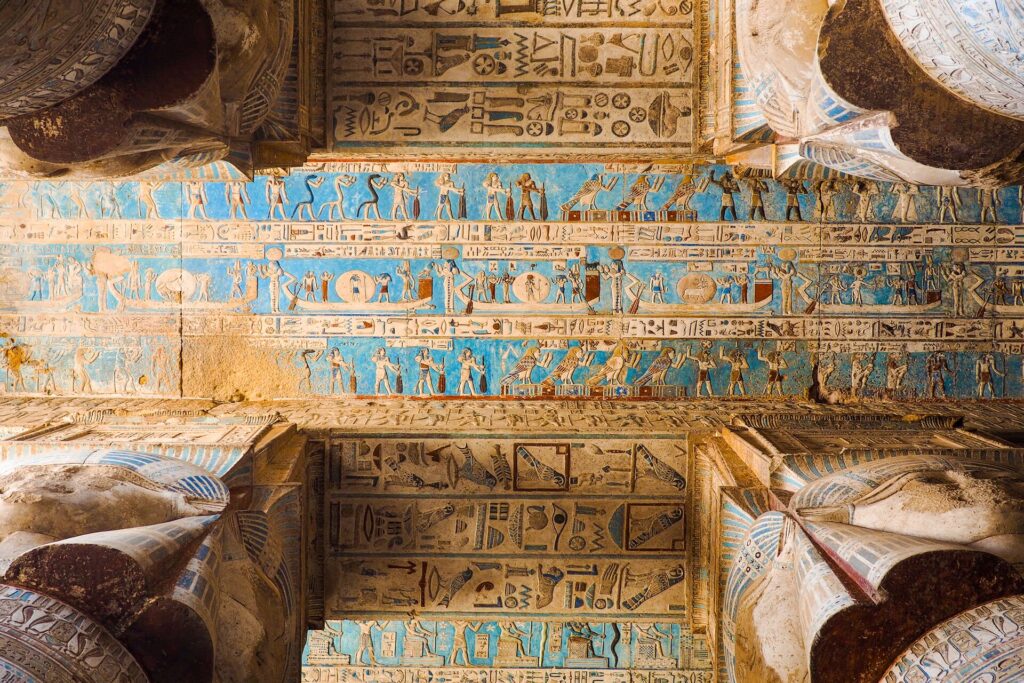 Egyptian hieroglyphics on a blue background on the ceiling of an ancient tomb in Egypt.