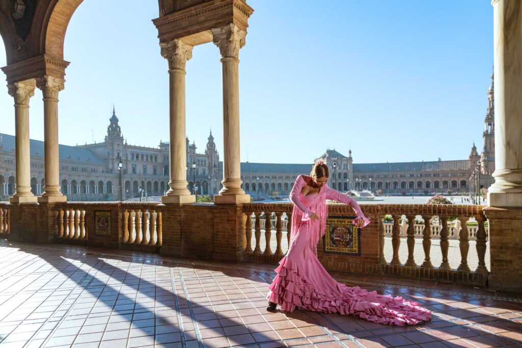 A Flamenco dancer in bright pink dances on the terrace of a Spanish palace.