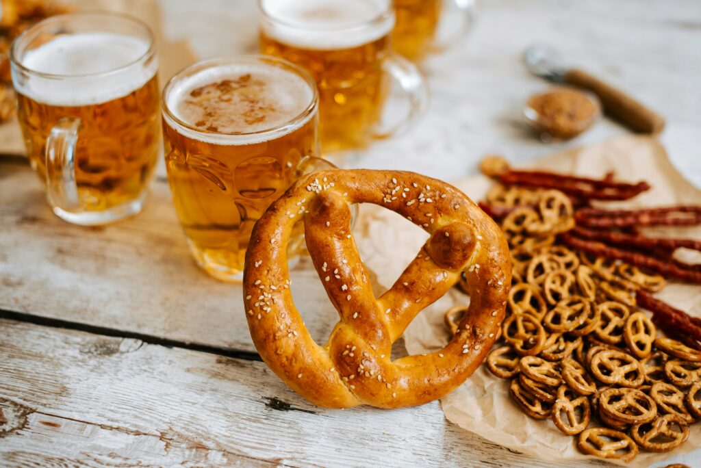 A traditional golden German pretzel and three glasses of beer.