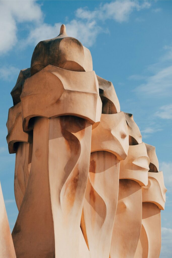 Sand coloured sculpturs with soft curves against a bright blue sky.