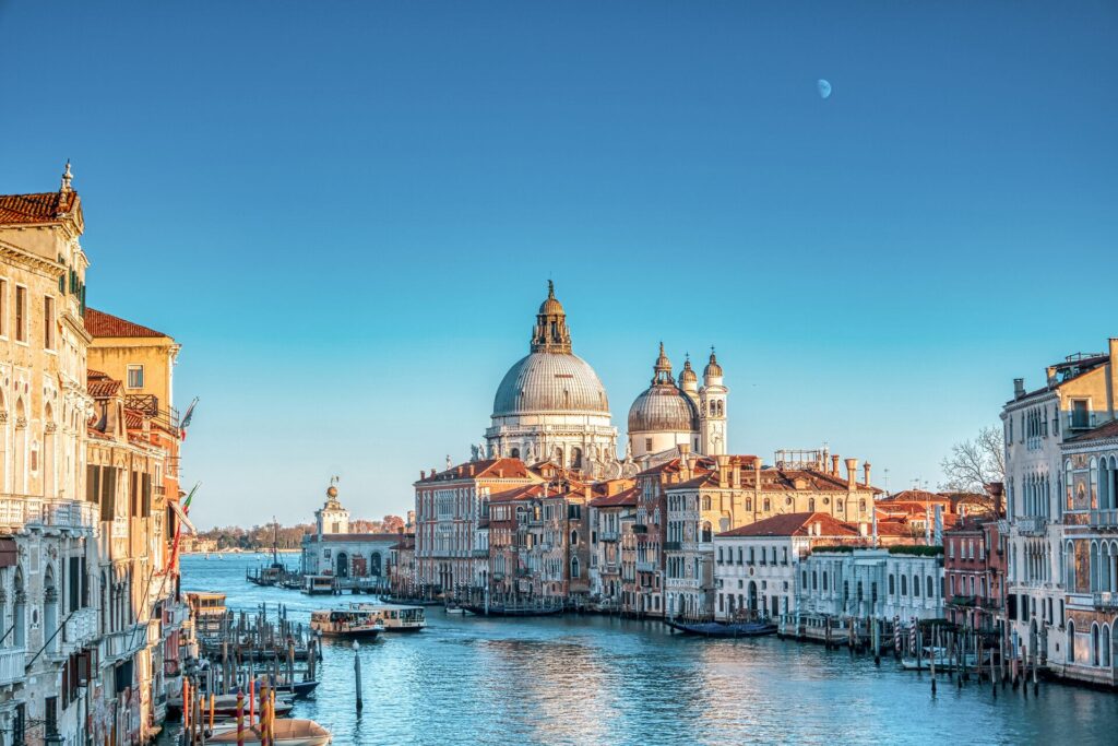 The ancient buildings of Venice, a great European city, with boats on the water and a clear blue sky.