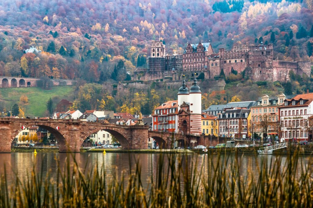 Red brick castle overlooks buildings, a bridge and river in Heidelberg, Germany.