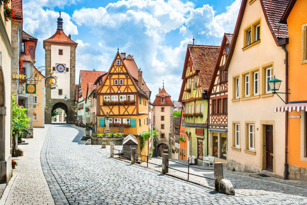 Colourful medieval buildings and a cobbled street with a bright blue sky at Rothenburg ob Der Tauber, a famous landmark in Germany