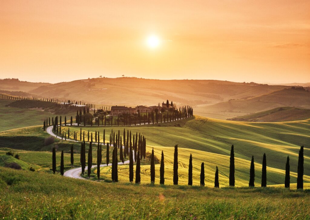 Winding road through Tuscan landscape at sunset