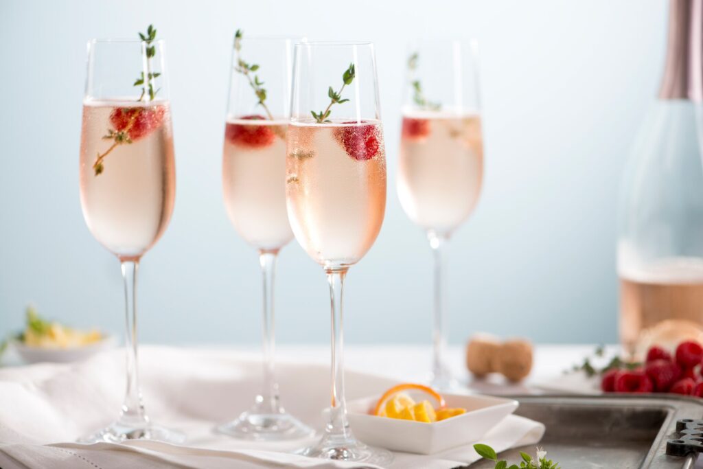 Four glasses of rose pink champagne with a strawberry in each