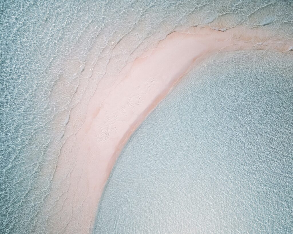 Aerial shot of pink sands rising amongst light blue waters.