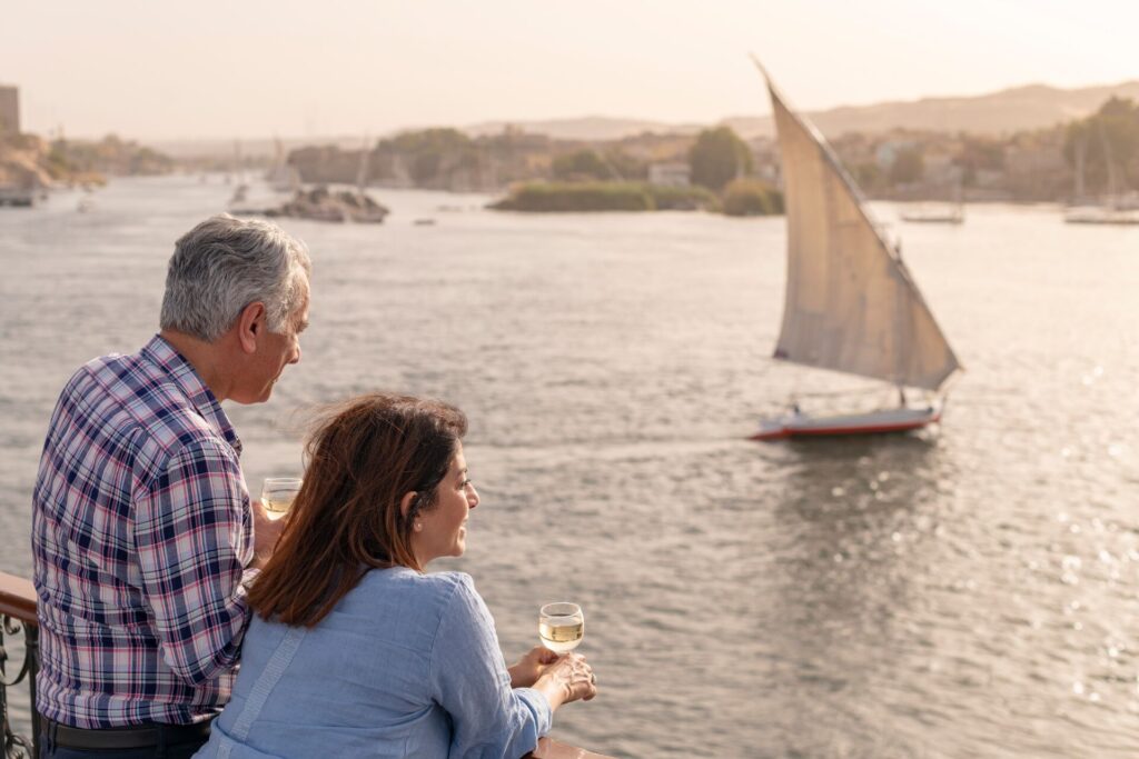 Couple look out over River Nile with a sailing boat on the water
