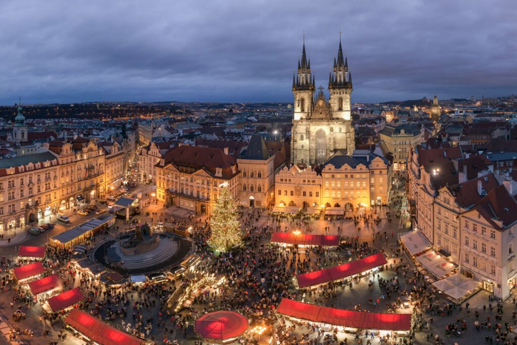 Aerial view of Prague's central square lit up with Christmas market stalls and full of people