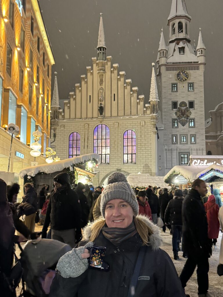 Insightful trivia competion winner stands in front of a church in the snow on Alpine Christmas markets tour
