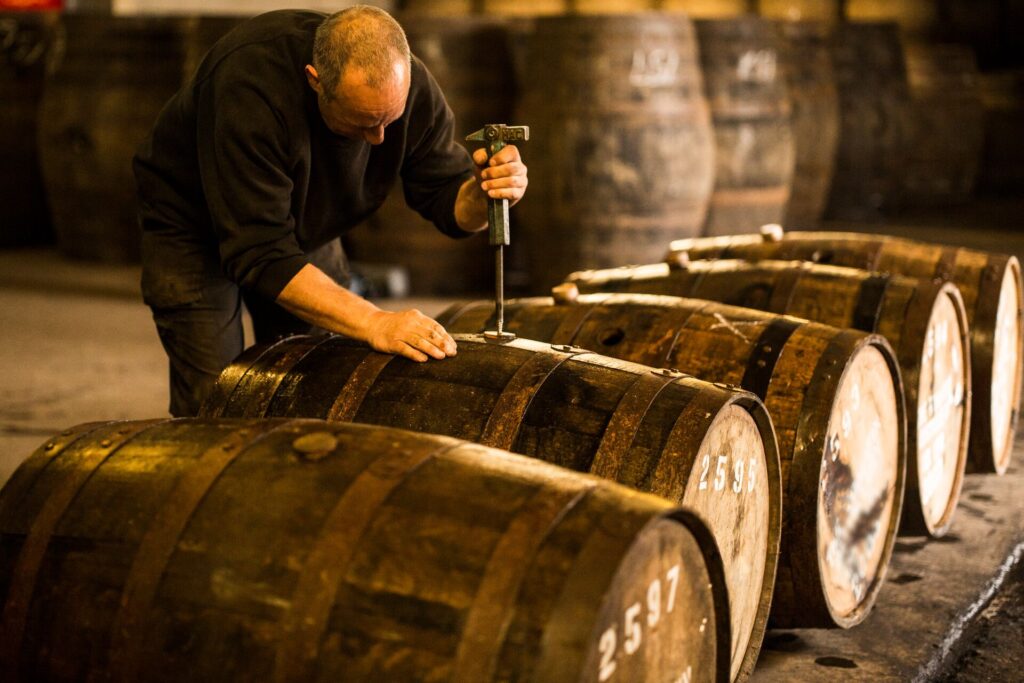 man opening a wooden whisky cask in distillery