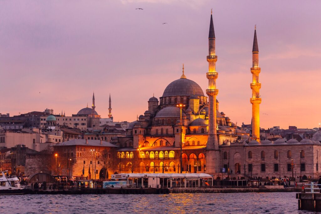 The Hagia Sophia in Istanbul, Turkey. It is lit up during the twilight hours of the day, when the sky is a dim amber.