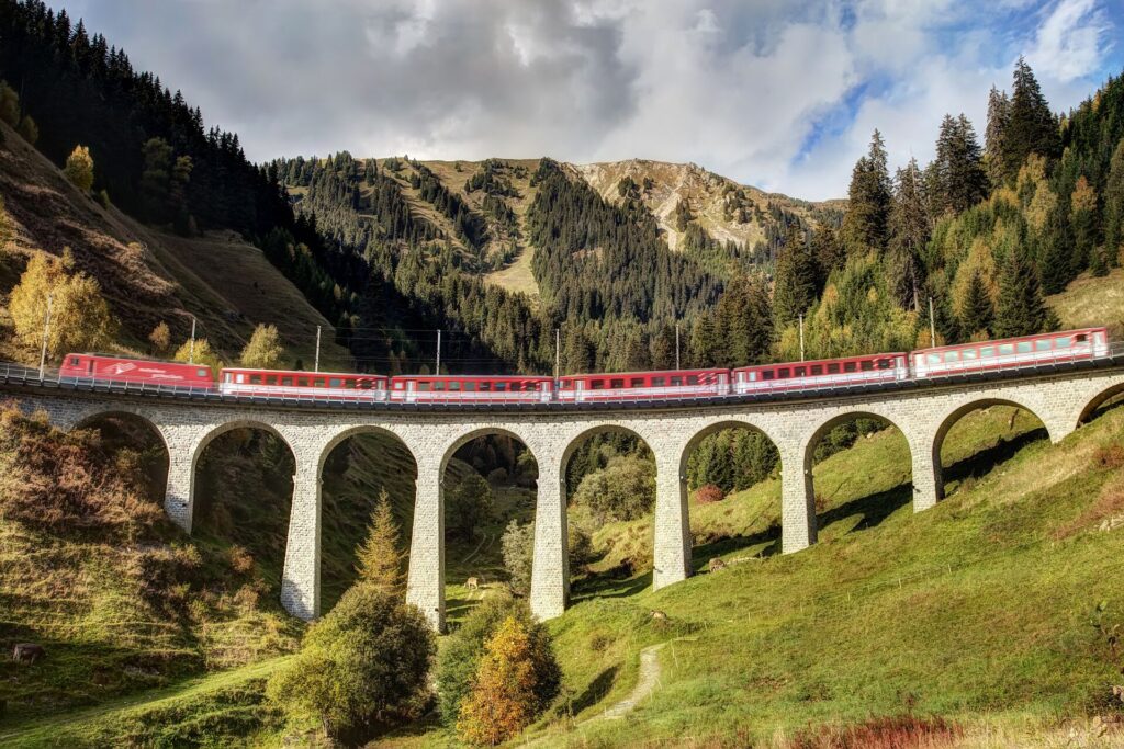 Red train passing on a viaduct in the Swiss Alps