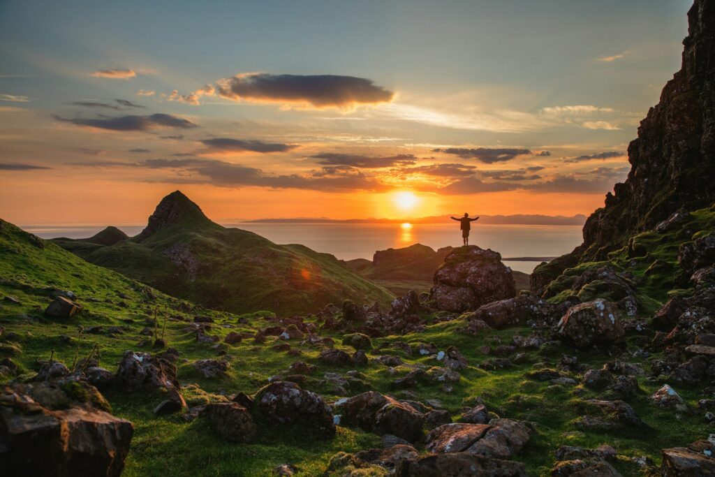 man standing on top of a mountain at sunset