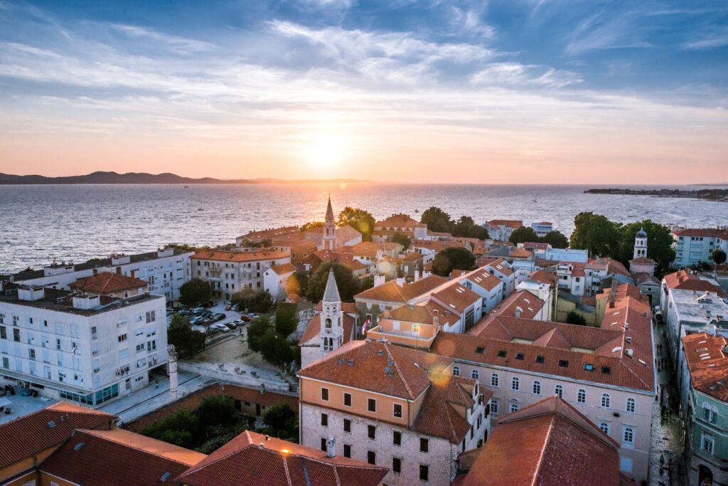 Aerial shot of red roofs and white buildings of Zadar, Croatia with the Adriatic sea in the background