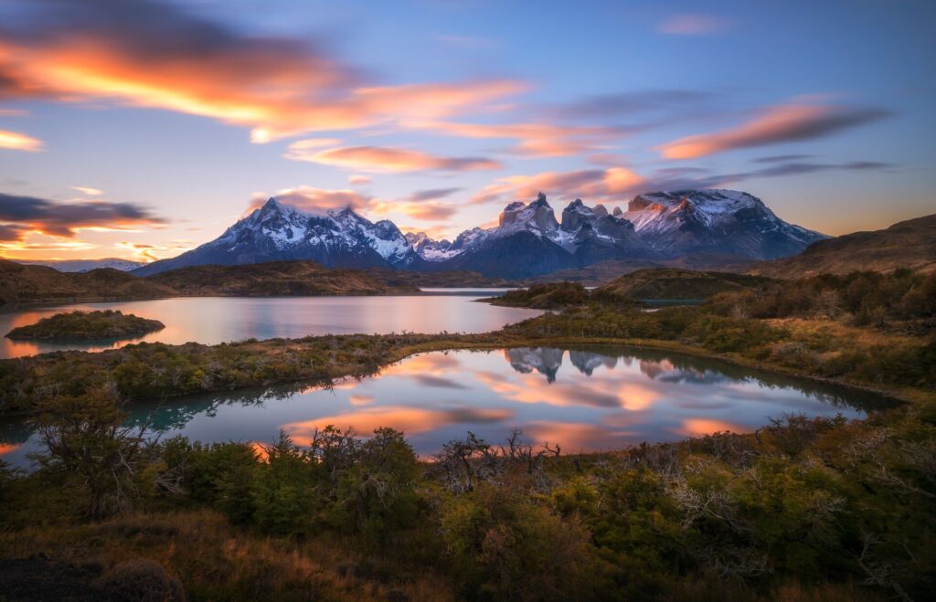 Chilean Patagonia: a lake reflecting pink clouds and snow-capped peaks which are stretching out into the horizon