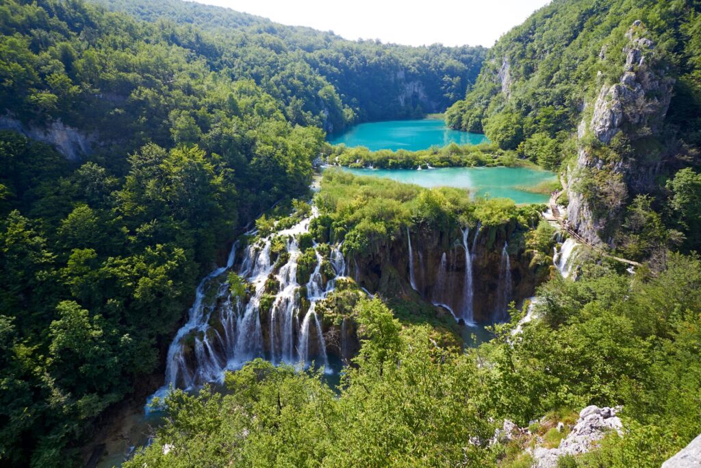 Blue lakes are joined by white cascading waterfalls surrounded by lush green forrests at Plitvice Lakes in Croatia