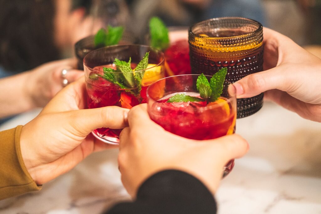 Three glasses of the bright red traditional Spanish drink sangria are held together.