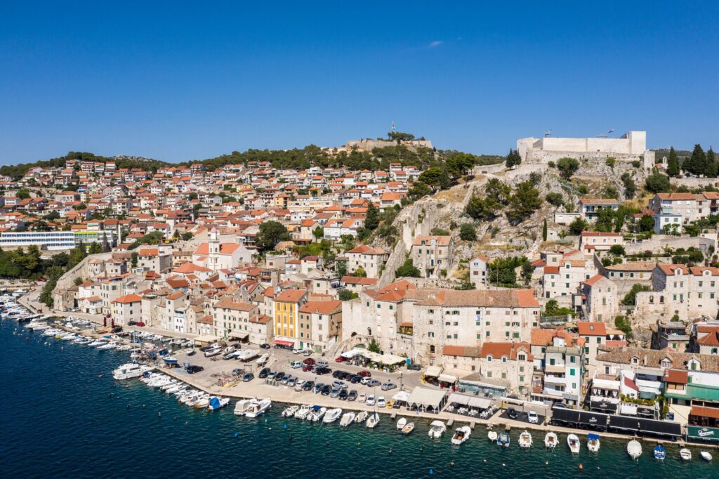 orange roofs and white houses rise up from a dark blue sea in Croatia