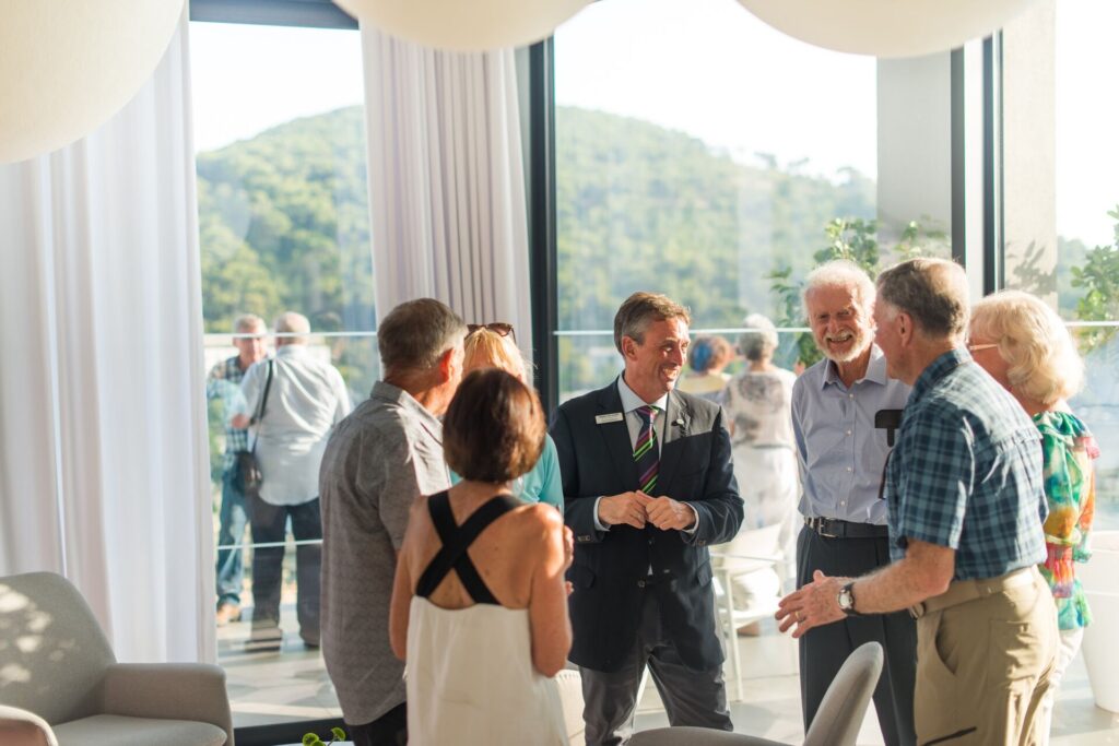 group of guests and travel director laughing and talking in a circle indoors