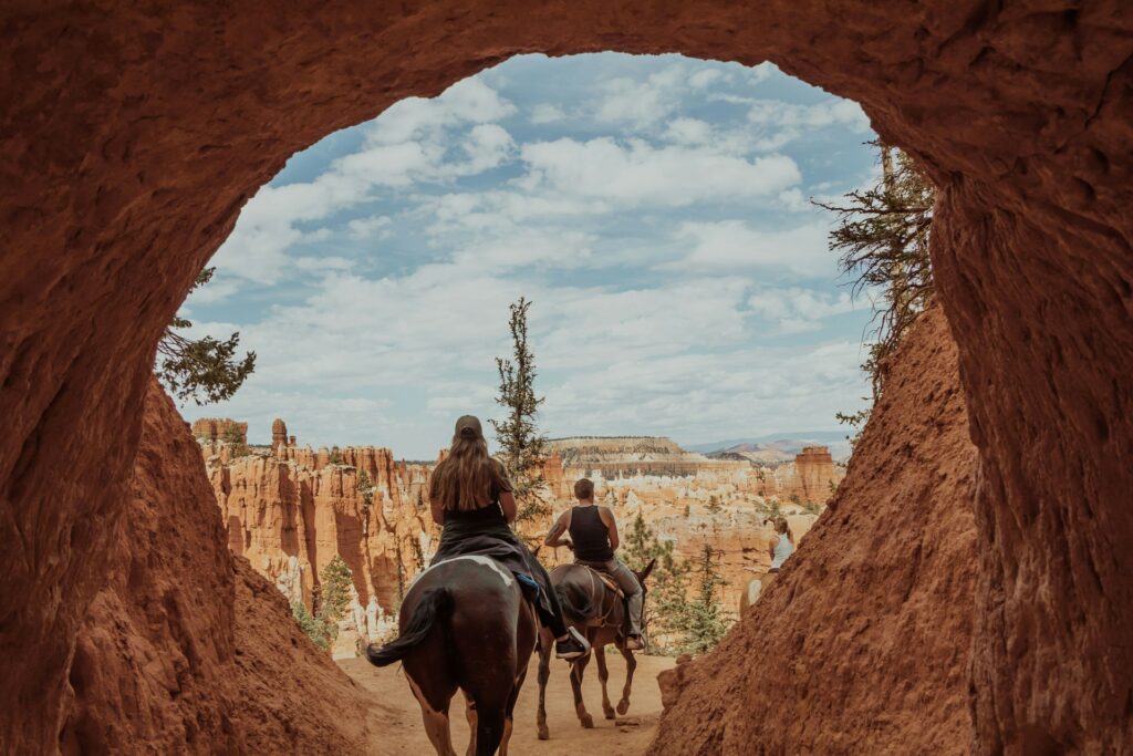 Couple riding horses through a natural archway in Bryce Canyon National Park