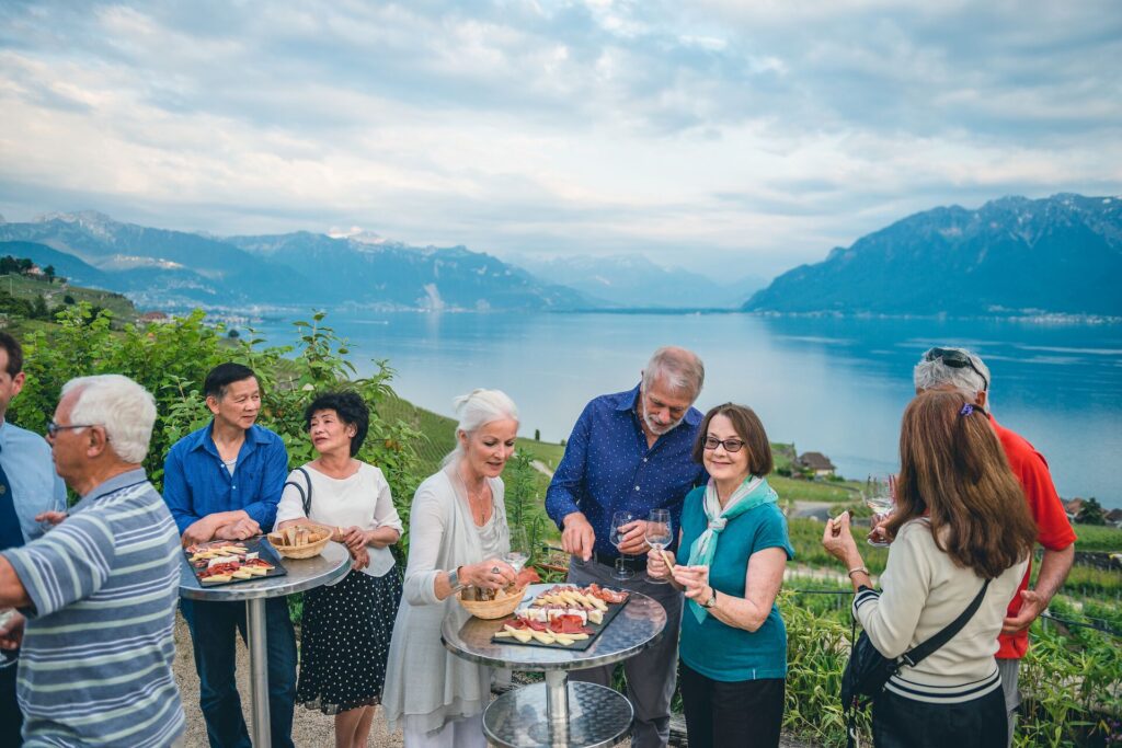 Group of Insight Vacations guests at a tasting by a large lake and mountains