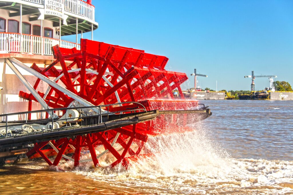 A close up shot of he bright red wheel of an old river boat on the Mississippi, against a bright blue sky