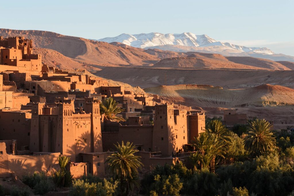 a kasbah and town in morocco, with the high atlas mountains in the background