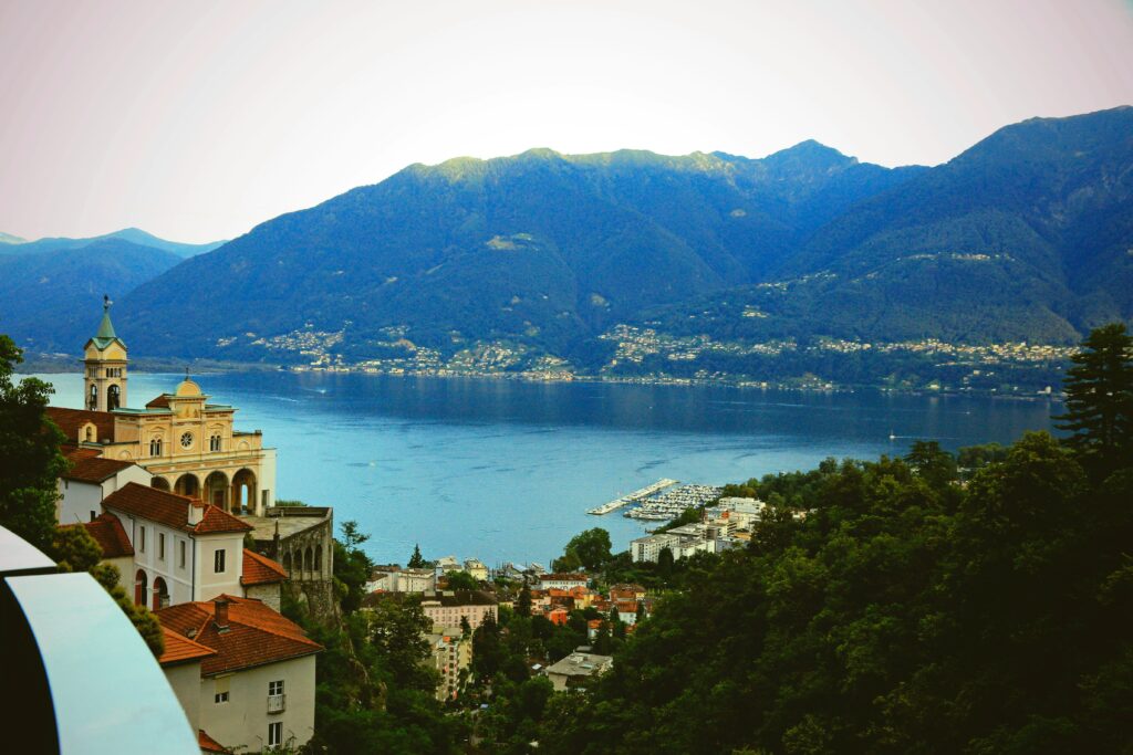 Aerial shot of mediterranean buildings and a blue lake with mountains in the background in Locarno, Switzerland.