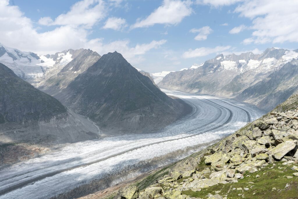 A wide white glacier snakes through grey mountains in Switzerland/