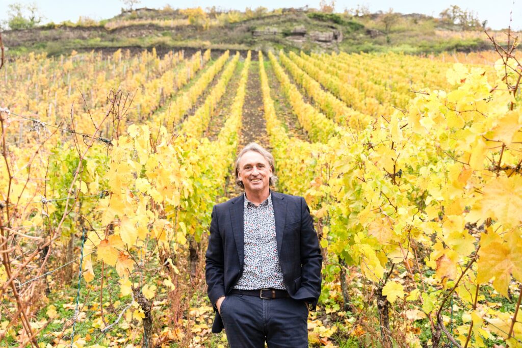 Insight Vacations Senior Travel Experiences Manager Tim Pendlebury stands smiling in a bright green an dornage vineyard.