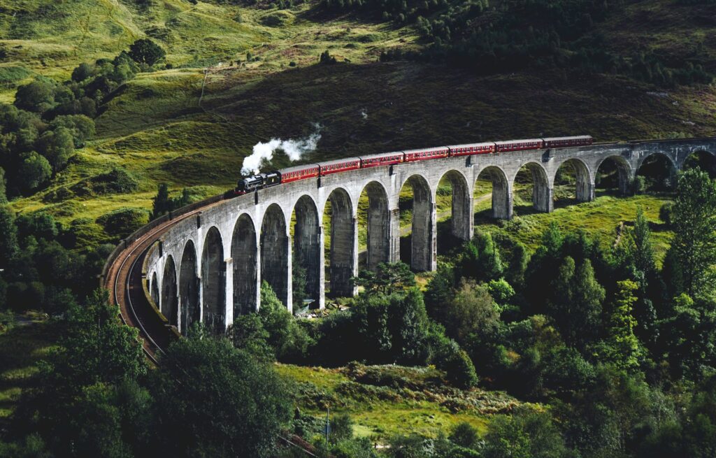 steam train coming round glenfinnan viaduct in Scotland