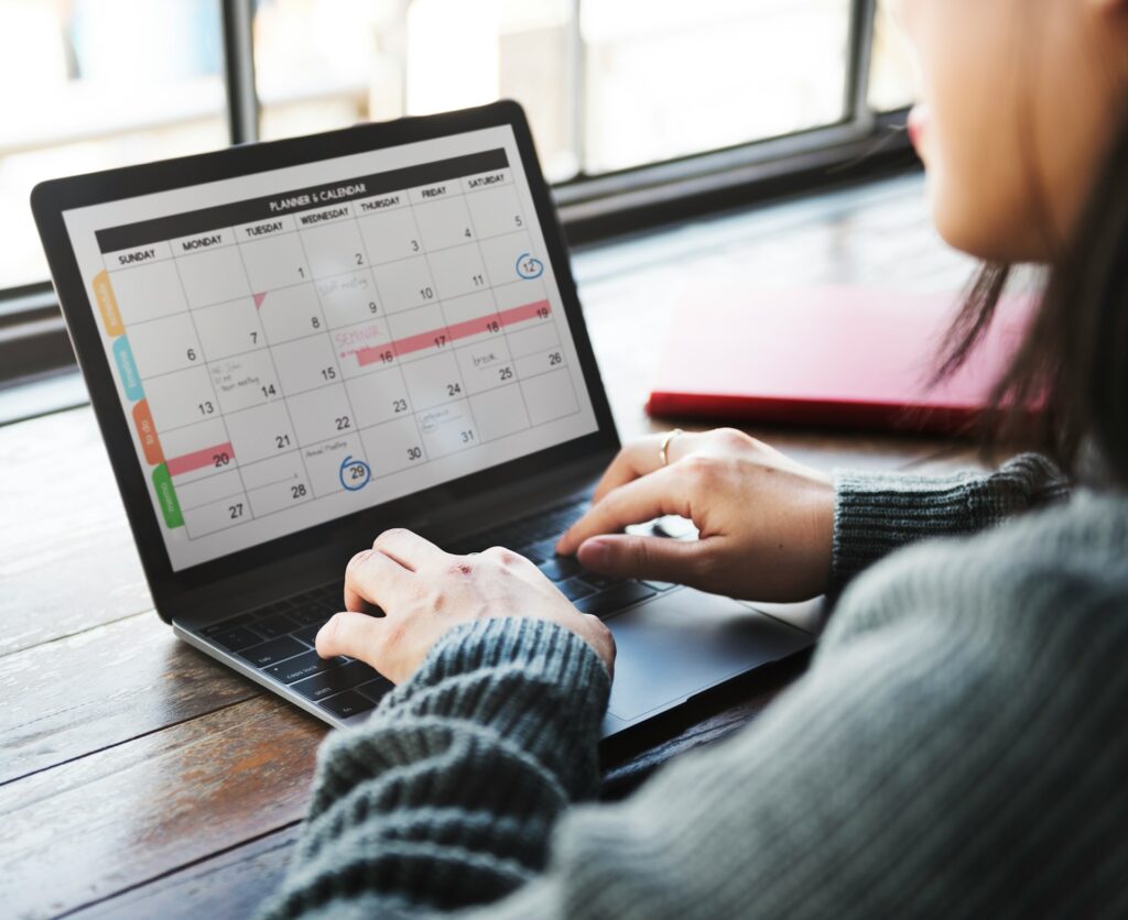 Close up of woman typing on a laptop with her calendar open