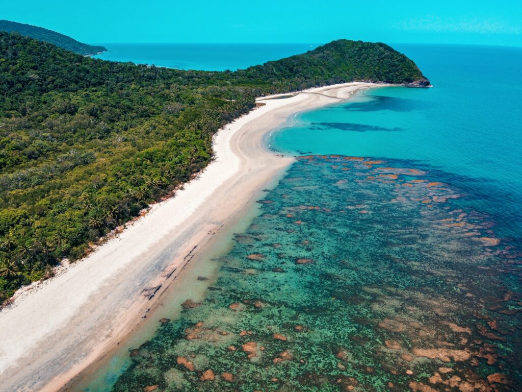 Long stretch of coastline seen above with coral reef in the shallow water near the beach