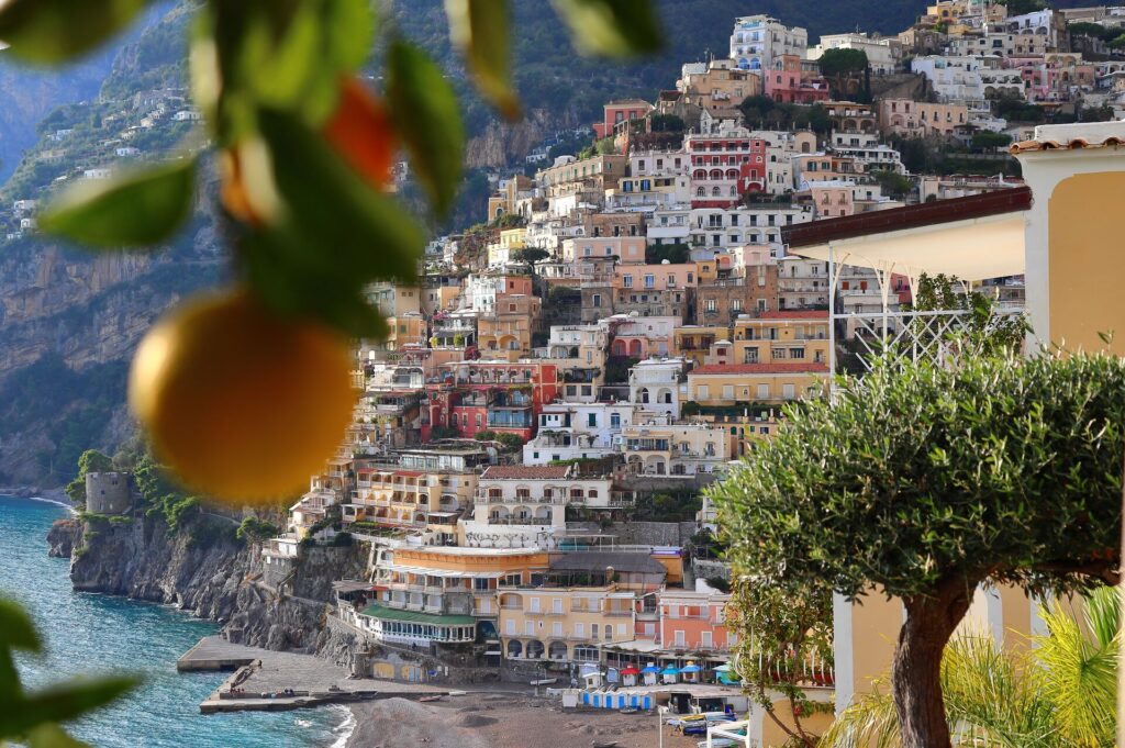 A Lemon in Positano, Italy, hangs in front of shot with buildings in the background, rising from the coast.