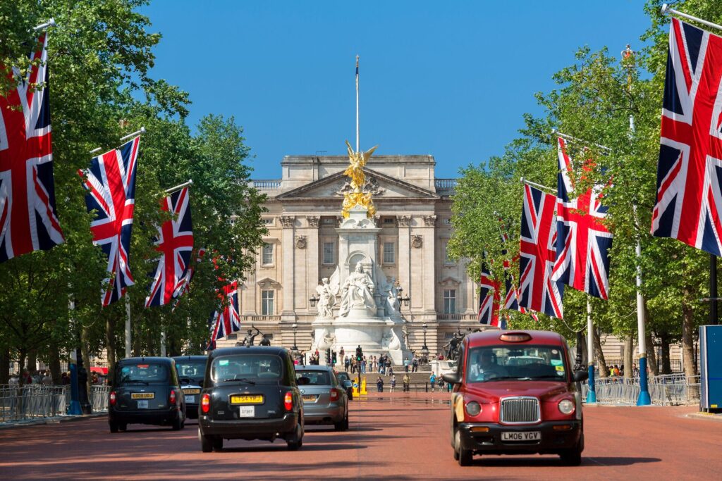 A view down the famous red bricked mall road to London's Buckingham Palace, with threes and flags along the sides.