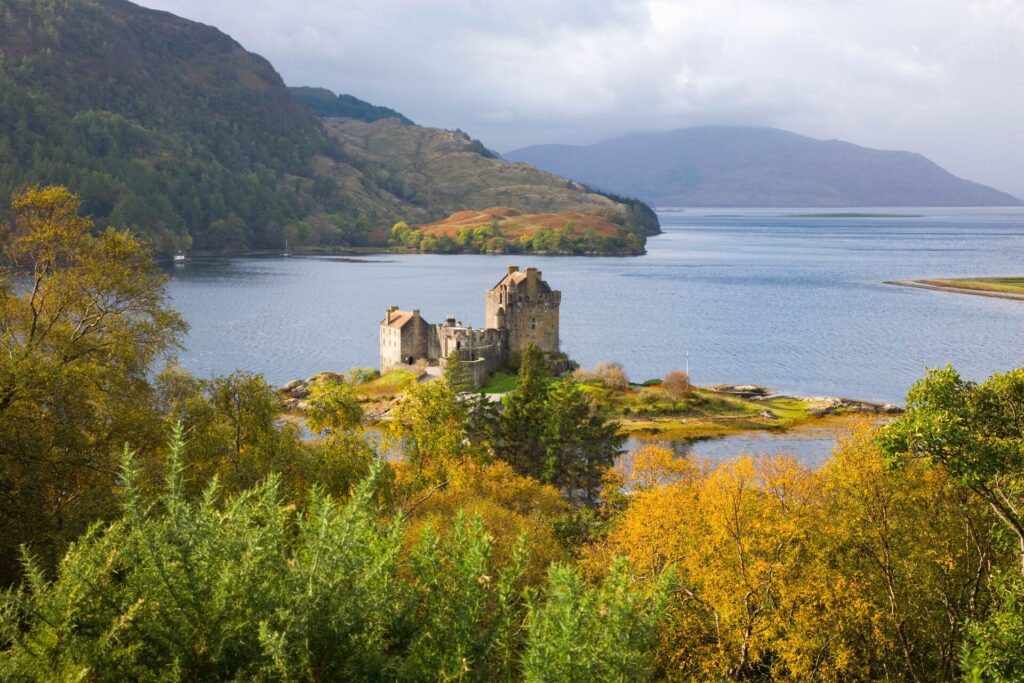 View over green and gold autumn trees to castle of Eilean Donan on Loch Duich near Dornie