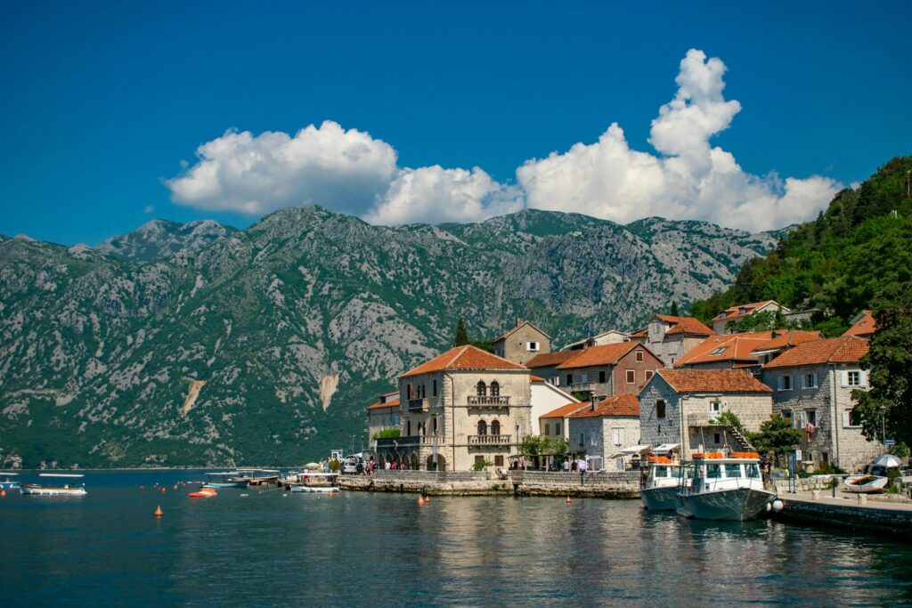 Old houses overlook a lake with mountains in the distance in Albania