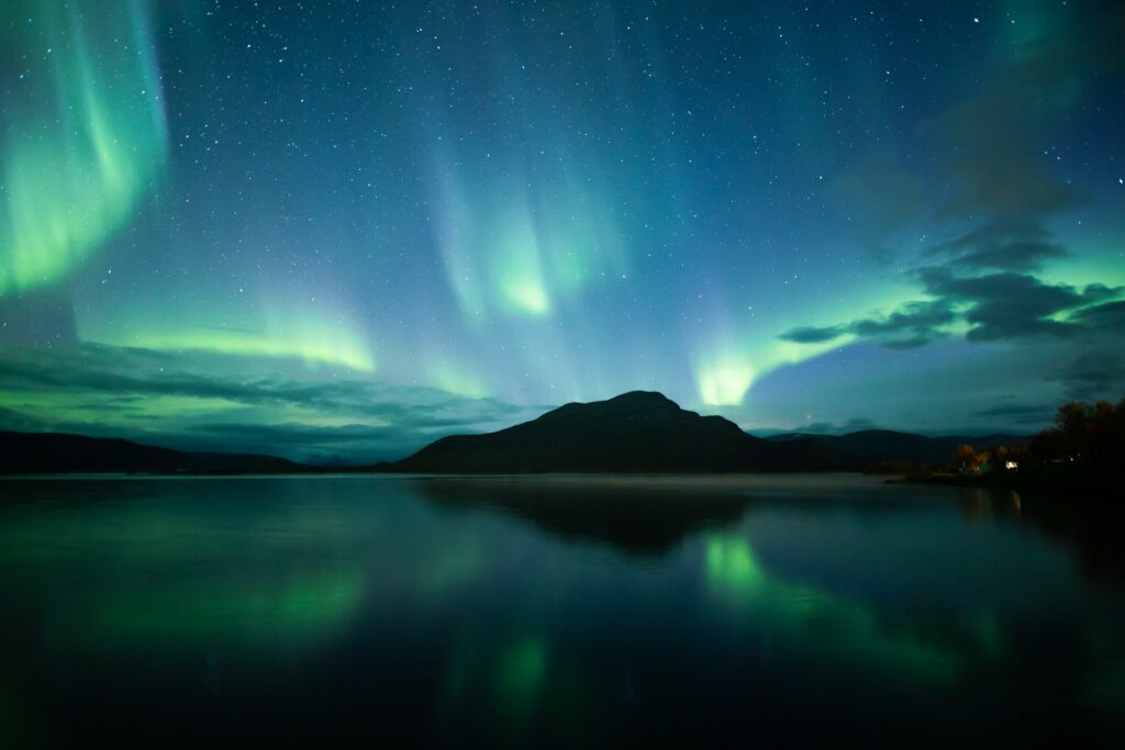 Night sky with northern lights and silhouetted mountain on the horizon