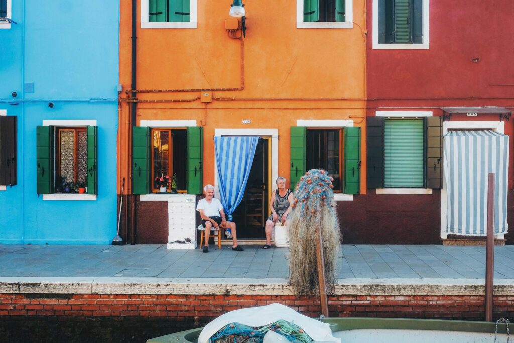 Man and woman sitting outside a brightly coloured house in Venice